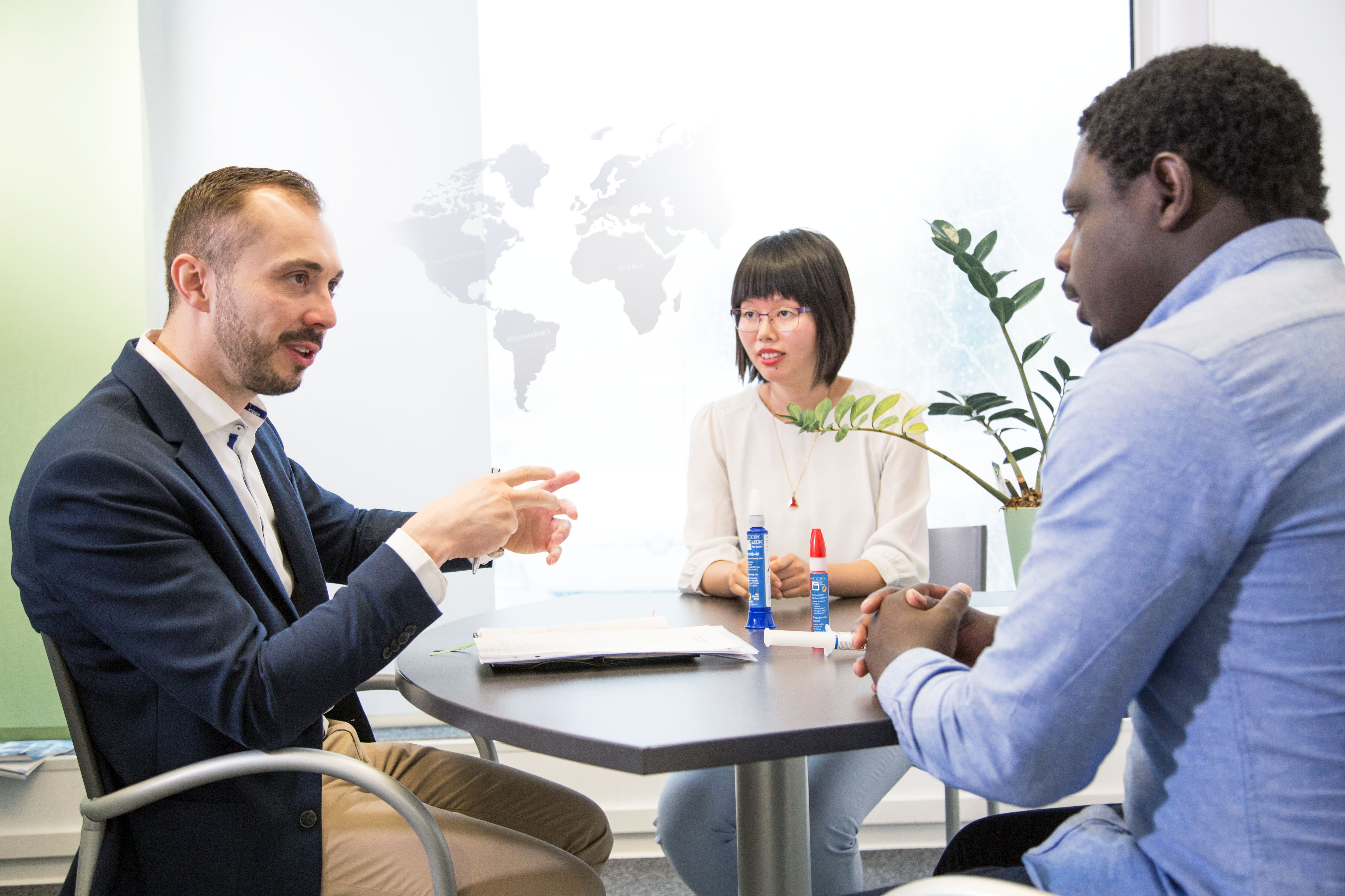 Two men and a woman sitting at a table talking to each other